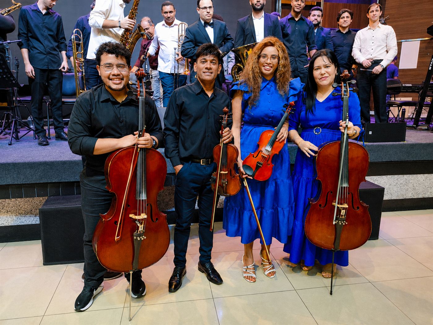 Os quatro integrantes do quarteto com seus instrumentos, em frente ao palco